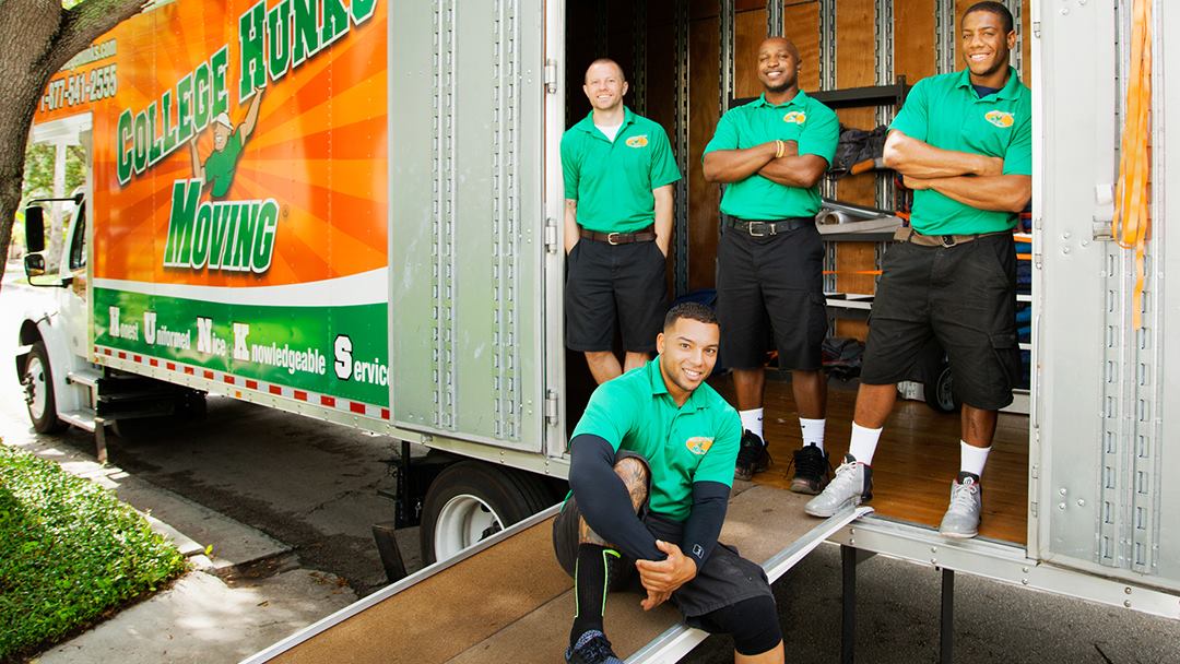 Four College Hunks Hauling Junk employees posing near their truck