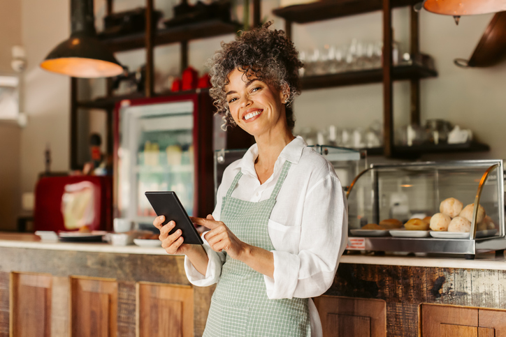 Smiling entrepreneur holding a digital tablet in her cafe stock photo